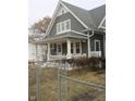 Charming gray home featuring a covered front porch with decorative white columns and a well-manicured, yet dormant, lawn at 21 S Warman Ave, Indianapolis, IN 46222