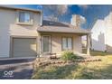 Charming condo with attached garage and front yard is surrounded by green grass and mature trees at 2552 Spring Hill Ct, Indianapolis, IN 46268