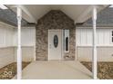 Close-up of the front entrance with stone accents, decorative pillars, and a stylish front door with oval glass at 32 Downing Dr, Trafalgar, IN 46181