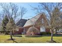 Brick home back view featuring mature trees, green lawn and meticulous landscaping at 351 Mallard Ct, Carmel, IN 46032