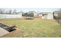 Large fenced-in backyard with an open grass area, storage shed, and a trampoline, perfect for recreation at 6830 Viola Ct, Indianapolis, IN 46237