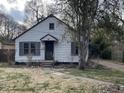 Quaint bungalow-style home with white siding, shutters, and mature trees in the front yard at 7016 Evanston Ave, Indianapolis, IN 46220