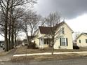 Street view of the two-story house with a brown roof and a quaint front porch lined by barren trees at 804 N Jameson St, Lebanon, IN 46052