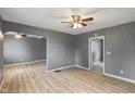 Open living room featuring light wood floors, gray walls, a ceiling fan, and an arched doorway at 818 S Grant St, Muncie, IN 47302