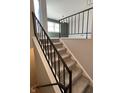 Carpeted stairway with sleek black railing leads to an open living area with natural light at 8315 Woodall Dr, Indianapolis, IN 46268