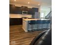 Modern kitchen with dark cabinets, a stainless steel microwave, and a breakfast bar with chairs at 10218 Cliff Ln, Indianapolis, IN 46239