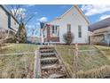 Charming home with a gabled roof, set on a raised yard with a chain-link fence and cement stairs at 125 Kansas St, Indianapolis, IN 46225