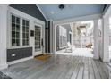 Inviting covered porch with gray wood flooring, white columns, seating and stylish decor at 5736 Central Ave, Indianapolis, IN 46220