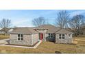 Charming single-story home featuring stone and brickwork, complemented by a vibrant red front door at 6890 Enclave Dr, McCordsville, IN 46055