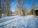 A snowy yard surrounded by bare trees and a wooden structure on a sunny day at 8676 W 1050 S, Fortville, IN 46040