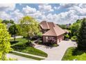 Aerial view of the home showcasing its manicured landscaping and circular driveway surrounded by mature trees at 10541 Titan Run, Carmel, IN 46032