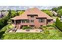 Aerial view of the backyard with patio, fire pit, outdoor dining, lush lawn and mature trees at 10541 Titan Run, Carmel, IN 46032