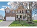 Charming two-story brick home with a well-manicured lawn and covered porch at 10887 Gresham Pl, Noblesville, IN 46060