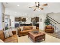 Open-concept living room showcasing stylish leather furniture, ceiling fan, wood floors and seamless flow to kitchen at 13553 Eastpark E Cir, Fishers, IN 46037