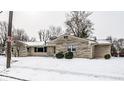 A single-story home featuring a stone facade, sidewalk, and a snow-covered yard at 1401 Castle Ave, Indianapolis, IN 46227