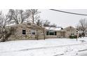 A single-story home featuring a stone facade, sidewalk, and a snow-covered yard at 1401 Castle Ave, Indianapolis, IN 46227