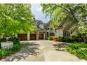 View of a home's three-car garage and stone brick facade and manicured front yard at 6560 Dawson Lake Dr, Indianapolis, IN 46220
