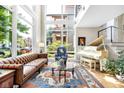 Bright living room with soaring windows, a leather couch, decorative rug, and grand piano near the stairs at 932 N Broadway St # 1, Indianapolis, IN 46202
