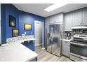 Updated kitchen featuring stainless steel appliances, gray cabinetry, quartz counters, and blue accent wall at 9505 Bay Vista W Dr, Indianapolis, IN 46250