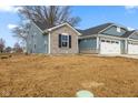 View of new home with blue siding and stone accents with an attached two car garage and driveway at 140 Mission Terrace Dr, Whiteland, IN 46184