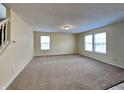 Spacious living room filled with natural light from two windows, and neutral carpet at 14457 Orange Blossom Trl, Fishers, IN 46038
