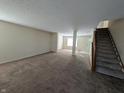 Open living room with carpet flooring, a staircase, and neutral paint, providing a versatile living space at 18924 Planer Dr, Noblesville, IN 46062