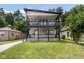 Charming two-story home featuring a spacious double-decker porch with stylish black railings and a well-maintained lawn at 4242 Winthrop Ave, Indianapolis, IN 46205