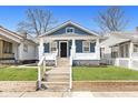 Charming blue bungalow featuring a covered porch, well-manicured lawn and inviting curb appeal at 520 N Parker Ave, Indianapolis, IN 46201