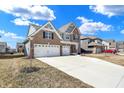 A sprawling driveway leads to a beautiful two-story home with brick accents and a three-car garage at 10412 Hamburg Dr, Fortville, IN 46040