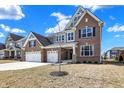 Well-manicured lawn complements this brick two-story home with a three-car garage and inviting front entrance at 10412 Hamburg Dr, Fortville, IN 46040