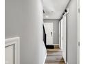 Hallway features a grey wall, wood floors, white doors, dark stairs and modern lighting at 3046 W New York St, Indianapolis, IN 46222