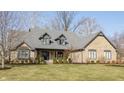 Lovely brick home with a gray roof, dormer windows, covered porch and mature landscaping on a green lawn at 13852 Silver Stream Dr, Carmel, IN 46032