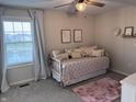 Neutral bedroom with patterned daybed, pink rug, ceiling fan, and bright natural light from the window at 15050 Bainbridge Ct, Westfield, IN 46074