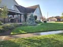 A beautifully landscaped lawn and outdoor patio area complement the exterior of this two-story brick home at 16 Torrey Pine Dr, Brownsburg, IN 46112