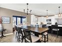 Open-concept dining area with a chandelier, hardwood floors, and an adjacent modern kitchen and living area at 1684 Hedley W Way, Avon, IN 46123