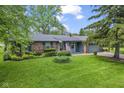 Single-story brick home with a well-manicured lawn, mature trees, and an American flag on display at 2818 S Irwin St, Indianapolis, IN 46203