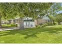 A single-story brick home featuring an attached two-car garage and mature trees on a well-manicured lawn at 2818 S Irwin St, Indianapolis, IN 46203