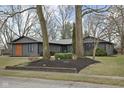 Well-maintained single-story home with mature trees, featuring a dark exterior at 3707 Chadwick Dr, Carmel, IN 46033