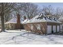 Rear exterior of a brick home with multiple garage doors and a snow-covered roof at 3762 N Foxcliff E Dr, Martinsville, IN 46151