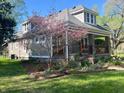 Charming gray home featuring a cozy front porch surrounded by a vibrant garden and flowering dogwood tree at 5533 Wilson Way, Jamestown, IN 46147