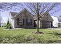 An eye-level side view of a brick home with a two-car garage and green lawn at 7425 Monterey Cir, Avon, IN 46123