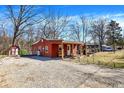 Exterior shot showing a gravel driveway and a charming red home with a covered porch and an American flag at 8657 S Nash Dr, Nineveh, IN 46164