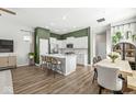Bright, open kitchen featuring white cabinets, a large island with seating, stainless steel appliances, and wood flooring at 1004 Astor Ln, Carmel, IN 46032