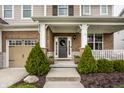 Welcoming front door with wreath, flanked by manicured evergreens at 12624 Teaberry Ln, Carmel, IN 46032