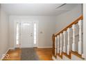 Inviting foyer with hardwood floors, a staircase with white spindles, and a welcoming front door at 2888 Prairie Stream Way, Columbus, IN 47203