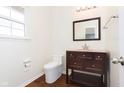 Well-lit half bathroom with a vanity, mirror, and toilet next to a window at 6333 Silver Moon Ct, Indianapolis, IN 46259