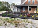 Charming home featuring a brick facade, inviting front porch, and meticulously landscaped flowerbeds at 695 N 650 W, Lebanon, IN 46052