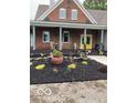 Inviting front porch with chairs, a yellow door, and meticulously landscaped flowerbeds add charm to this lovely brick home at 695 N 650 W, Lebanon, IN 46052