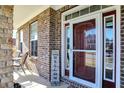 Inviting covered porch with stone pillars, featuring a welcome sign and outdoor seating area at 7800 Walker Cup Dr, Brownsburg, IN 46112