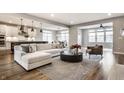 Bright and open living room with a modern sectional sofa, hardwood floors, and adjacent kitchen at 804 Whispering Oaks Dr, Carmel, IN 46032